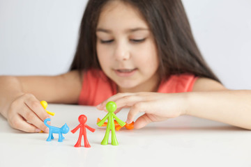 Obraz na płótnie Canvas Happy traditional family figurines. A small child plays with colored plastic figures. Mom, dad, brother, sister, siblings. Family symbol. Adoption. Full family. Face out of focus.