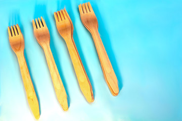 Disposable ecological wooden bamboo fork  pattern on light blue background. Environment friendly flat lay with free copy space for text. Selective background