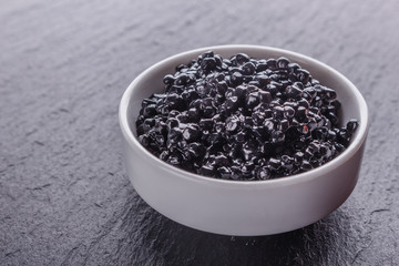 black caviar in a bowl on a dark stone background