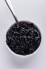 black caviar in a bowl on a white acrylic background