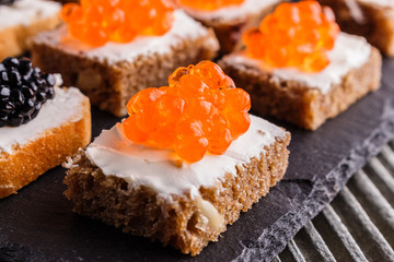 Snack with red and black caviar on a stone plate