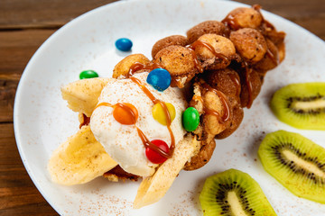 Ice cream ice cream in a waffle cone with sweets and fruit syrup