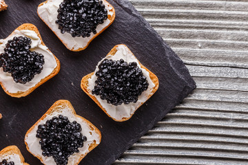 Snack with red and black caviar on a stone plate