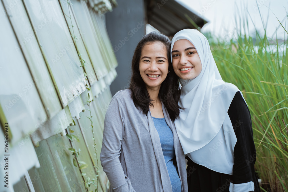 Wall mural asian and muslim middle eastern woman friend together smiling to camera