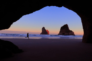 view from the cave of wharariki beach landmark of popular tourist place in south new zealand, tasman sea, running silhouette