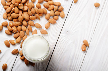 Milk or yogurt in mason jar on white wooden table with almonds aside flat lay view