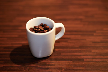An espresso cup on a table filled with roasted coffee beans