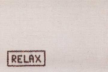 Relax sign made from roasted coffee beans, aligned bottom-left on linea texture.