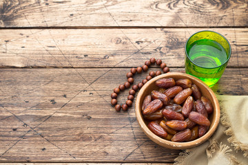 Dried dates fruits and a glass of water on a wooden table. Traditional fast breaking, Muslims evening meal during holy Ramadan