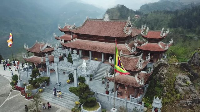Beautiful Chinese temple Buddhism on top mountain  Fansipan Vietnam Sapa. Tile roof decor stucco dragons. Asian style authentic culture high mountains landscape background. Aerial approach