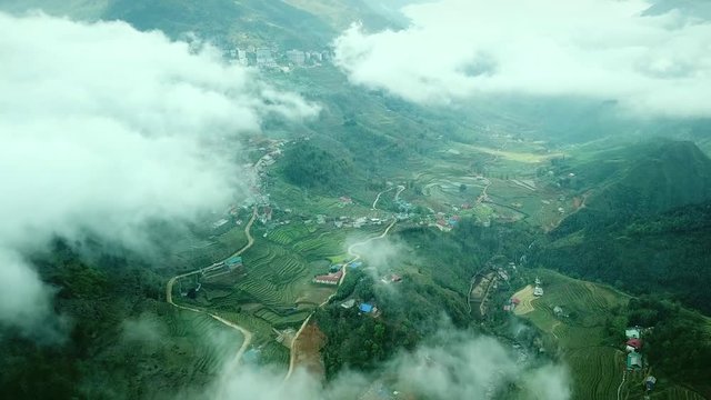 Aerial great height view through clouds fog old village rice fields green texture cascades drawing. Canyon high mountains. Sa Pa Capa Vietnam. Beautiful Natural agricultural landscape. Tourism Sight