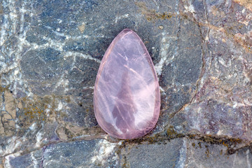Rose quartz kaboshon on rocky background