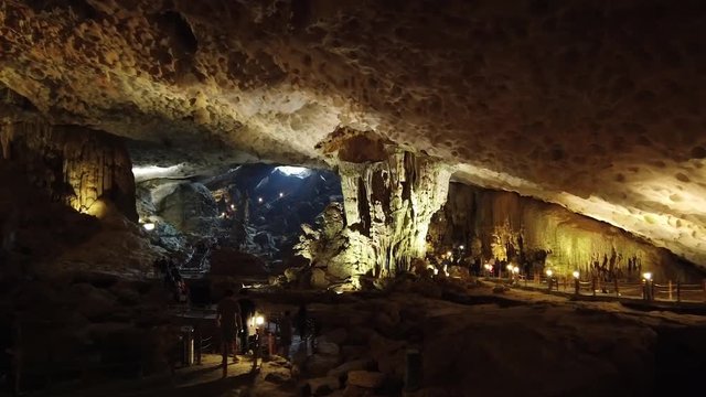 Surprise magnificent dark Cave hall ceiling is decorated with stalagmites stalactites structure texture Bo Hon Island charming Halong Bay. tourist attraction people walk. Vietnam Asia. Gimbal Dolly