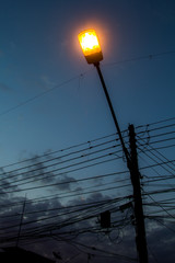 Street lamp glowing against a dusk sky with wires © joangasconcomas