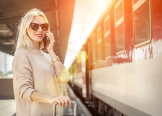 Fototapeta premium Blonde woman with her luggage stay and speak in her mobile near
