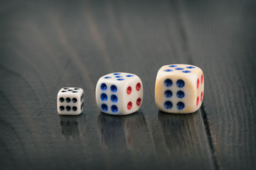 three dice of different sizes on a dark blurred background. toned