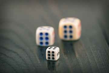 three dice of different sizes on a dark blurred background. toned