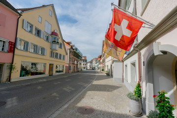 the main street of Steckborn in northeastern Switzerland with ist historic buildings and Swiss flag in the foreground