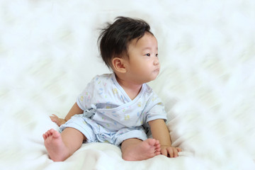 Asian cute baby, black and short hair, sitting on white mattress with curious and innocent face