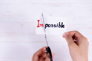 Motivation concept, Woman hands holding card impossible with scissor.