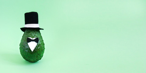 Fototapeta na wymiar Fresh avocado in an elegant suit of black and white hats, shirts and bow ties on bright green background. Minimal concept for wedding holidays card, party invitations. Front view, close up, copy space