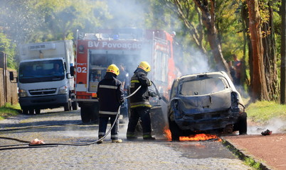Burning car on the road with fire department