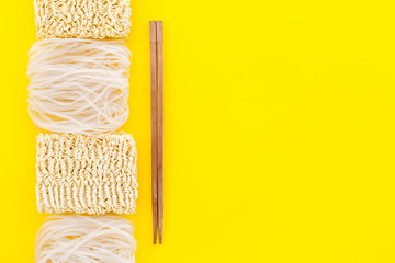 Rice vermicelli, noodles, sticks to cook Chinese and Japanese food design on yellow background top view copy space