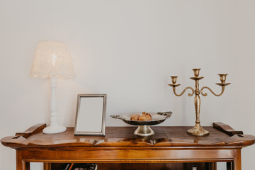 chest of drawers with a lamp candelabra and a vase against a white wall- Image