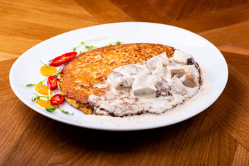Potato pancakes in white mushroom sauce. Draniki - potato fritters. potato pancakes. The naitonal dish of Belarus, Ukraine and Russia