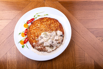 Potato pancakes in white mushroom sauce. Draniki - potato fritters. potato pancakes. The naitonal dish of Belarus, Ukraine and Russia. Top view