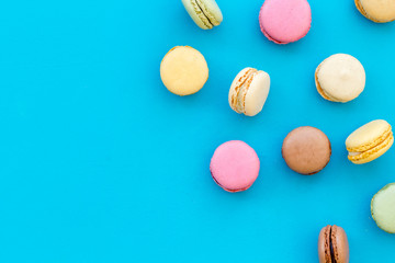 Obraz na płótnie Canvas Brignt macarons for sweet break on blue background top view mock up