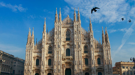 The cathedral of Milan with Gothic style of architecture and birds fly in the sky. Duomo di Milano in Italy
