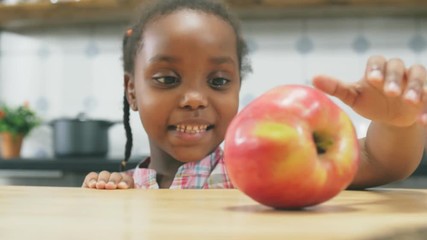 Little Afro American girl grabbing red apple - Powered by Adobe