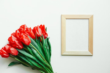 Flatlay of tulips and photo frame on white background. Copy space. Empty space.