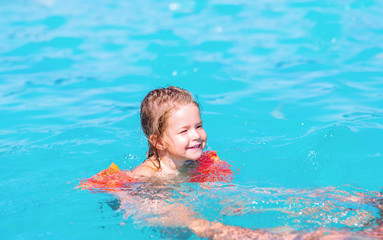 Fototapeta na wymiar Young child is swimming in a pool -Cute kid swimming in the pool.