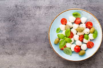 Delicious caprese salad with ripe cherry tomatoes and mini mozzarella cheese balls with fresh basil leaves.