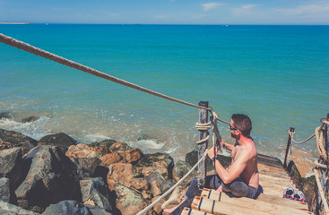 Obraz premium Caucasian young shirtless man making a great knot on strong rope