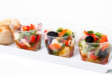 Aperitivos de verduras en vaso sobre bandeja blanco. Vista de frente