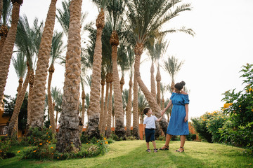 Stylish mother and handsome son having fun on a green lawn. Happy family concept. Beauty nature scene with family outdoor lifestyle. Happy family resting together. Mothers day