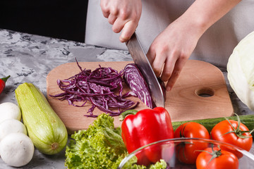 a young woman in a gray apron cuts red cabbage