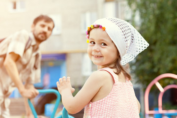 Little girl with dad on a swing