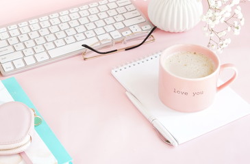 Pastel colors flat lay top view women's office desk . Female workspace with laptop, white flowers,  accessories, notebooks, glasses, cup of coffee on pale pink background. Copy space. 