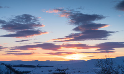 Fototapeta na wymiar Cloudy sunset over Swedish Lapland on a winters day. Ahkka, Sweden.