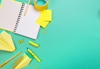 Creative, fashionable, minimalistic, school or office workspace with yellow supplies on cyan background. Flat lay.