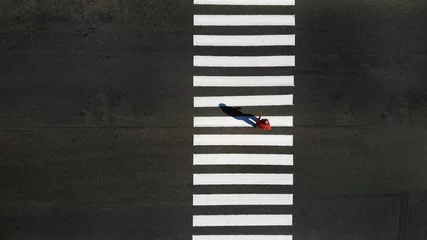 Fotobehang One pedestrian crossing zebra crosswalk, aerial, top view © Dmytro