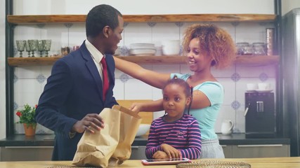 African woman and daughter meeting father in kitchen