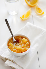 Trendy healthy homemade citrus lemon jam or confiture in a bowl on a white wooden background top view.Delicious dessert for Breakfast. Fruit preservation.Vertical orientation