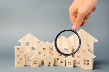 Wooden houses and magnifying glass. Property valuation. Home appraisal. Choice of location for the...