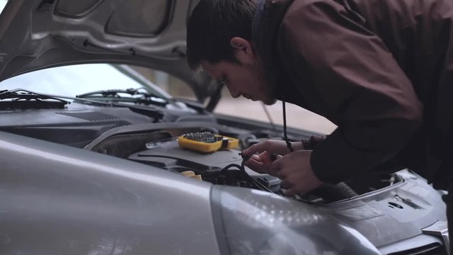 man repairing broken car in outdoor. The car broke down on the road. Unforeseen situation. Close-up. Slowmotion.