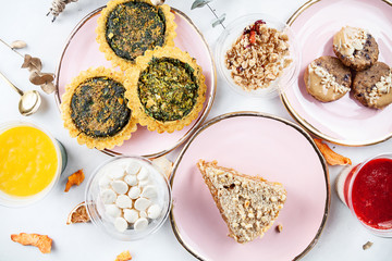 Top view on served food table. Healthy vegan pastry, dessert on marble table. quiche, cookie, cake, trifle, granola. Copy space for design. Healthy breakfast flat lay
